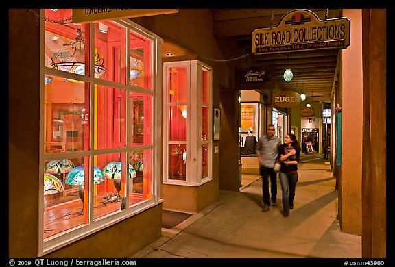 Couple walking by night in front of gallery. Santa Fe, New Mexico, USA