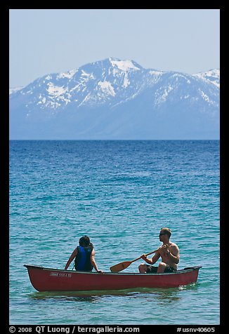 Man and woman in canoe with snowy mountains in the background, Lake Tahoe, Nevada. USA