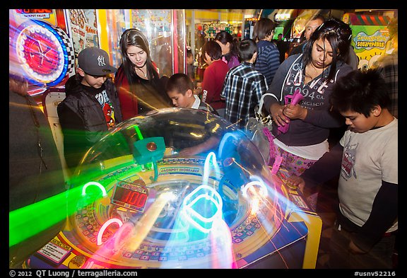 Family plays arcade game with spining lights. Reno, Nevada, USA