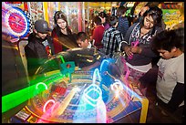 Family plays arcade game with spining lights. Reno, Nevada, USA ( color)