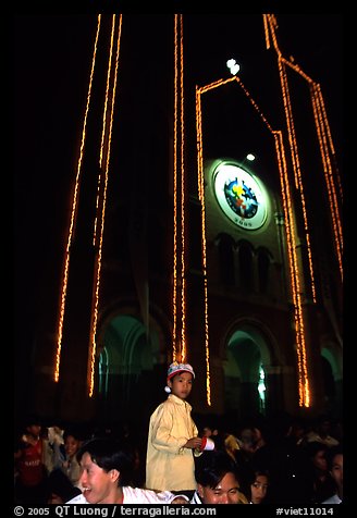 Child with christmas hat in front of St Joseph Cathedral on Christmas eve. Ho Chi Minh City, Vietnam (color)