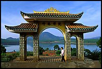 Pagoda gate with woman standing near lake. Da Lat, Vietnam ( color)