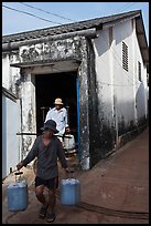 Workers carrying out containers of nuoc mam, Duong Dong. Phu Quoc Island, Vietnam (color)