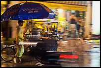Man riding riding food cart in the rain. Ho Chi Minh City, Vietnam ( color)
