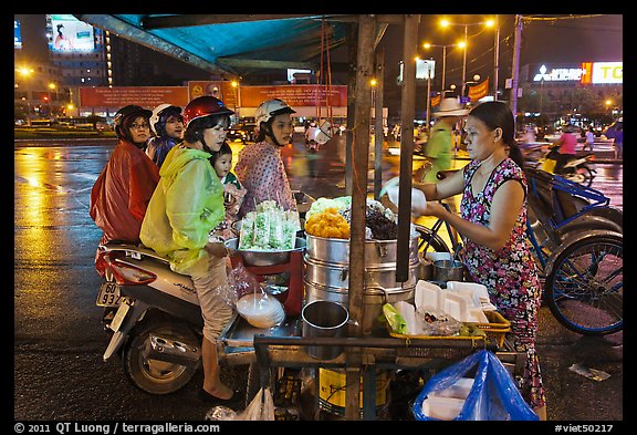 Women riding motorbikes buy sweet rice. Ho Chi Minh City, Vietnam (color)