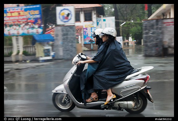 Women ride motorcycle in the rain. Ho Chi Minh City, Vietnam (color)