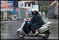 Women ride motorcycle in the rain. Ho Chi Minh City, Vietnam ( color)