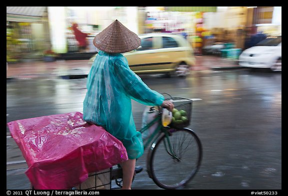 Woman rides bicycle in the rain. Ho Chi Minh City, Vietnam (color)