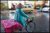 Woman rides bicycle in the rain. Ho Chi Minh City, Vietnam (color)