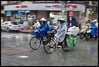 Women riding bicyles in the rain. Ho Chi Minh City, Vietnam (color)