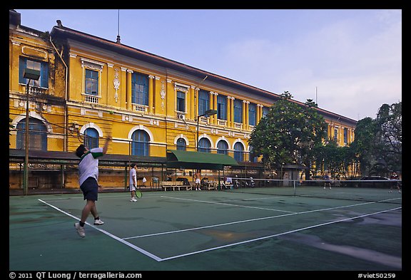 Men play tennis in front of colonial-area courthouse. Ho Chi Minh City, Vietnam (color)