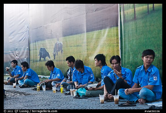 Uniformed students sitting in front of backdrops depicting traditional landscapes. Ho Chi Minh City, Vietnam