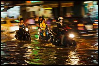 Women riding motorcyles at night in water. Ho Chi Minh City, Vietnam ( color)