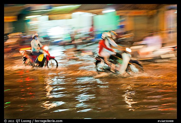 Motion-blured exposure of riders on flooded street at night. Ho Chi Minh City, Vietnam