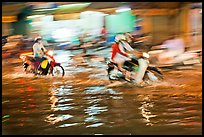 Motion-blured exposure of riders on flooded street at night. Ho Chi Minh City, Vietnam