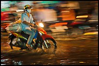 Motorcycle rider photographed with panning motion at night. Ho Chi Minh City, Vietnam (color)