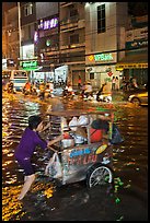 Vendor pushing foot car into the water at night. Ho Chi Minh City, Vietnam ( color)
