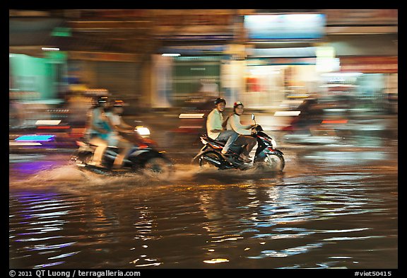 Motorcycles riding through the water on street with motion. Ho Chi Minh City, Vietnam