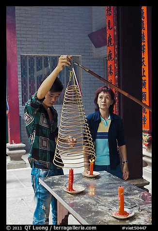 Man getting ready to hang incense coil, Thien Hau Pagoda, district 5. Cholon, District 5, Ho Chi Minh City, Vietnam (color)