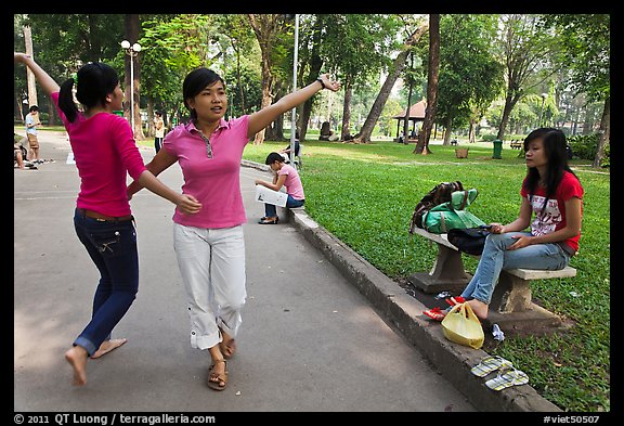Young women dancing to sound of mobile phone, Tao Dan Park. Ho Chi Minh City, Vietnam