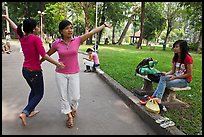 Young women dancing to sound of mobile phone, Tao Dan Park. Ho Chi Minh City, Vietnam ( color)
