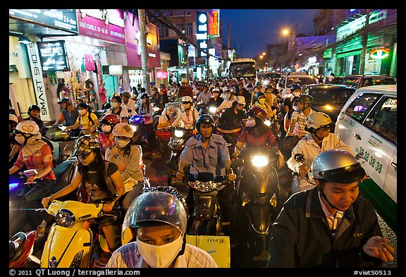 Street packed with motorcycles and vehicles at dusk. Ho Chi Minh City, Vietnam (color)