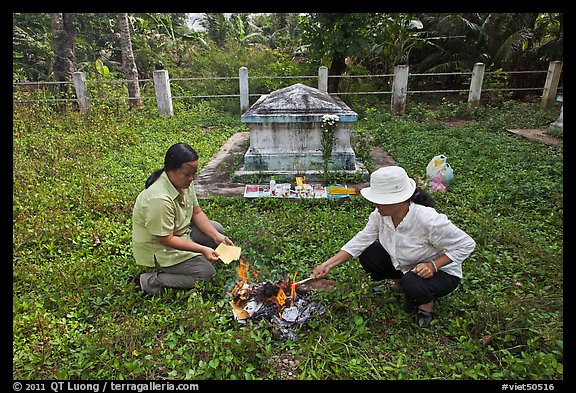 Women burning notes as offering in cemetery. Ben Tre, Vietnam