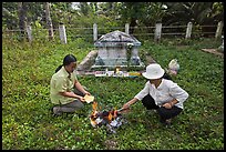 Women burning notes as offering in cemetery. Ben Tre, Vietnam