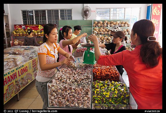 Women weighting coconut candy in retail store. Ben Tre, Vietnam (color)