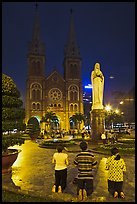 Family in prayer outside Notre-Dame Basilica at night. Ho Chi Minh City, Vietnam (color)