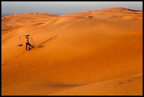 Red sand dunes and woman with carrying pole and baskets. Mui Ne, Vietnam ( color)