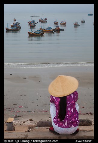 Woman with conical hat sitting above fishing fleet. Mui Ne, Vietnam
