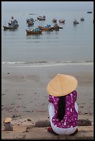 Woman with conical hat sitting above fishing fleet. Mui Ne, Vietnam (color)