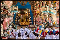 Dignitaries (in colored robes) and other followers praying at the Main hall, Cao Dai temple. Tay Ninh, Vietnam (color)