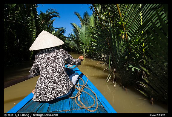 Woman rowing boat in canal lined up with vegetation, Phoenix Island. My Tho, Vietnam