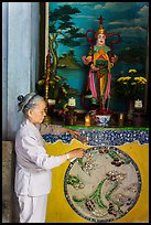 Woman lighting incense at side altar. Da Nang, Vietnam (color)