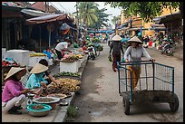 Woman pushing cart on market street. Hoi An, Vietnam (color)