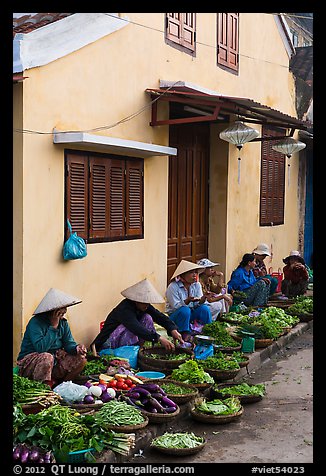 Vegetable vendors sitting in front of old house. Hoi An, Vietnam