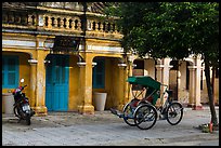 Motorcyle and cyclo in front of old townhouses. Hoi An, Vietnam (color)