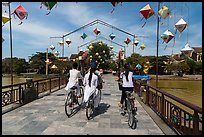 Girls on bicycle cross bridge festoned with lanterns. Hoi An, Vietnam ( color)