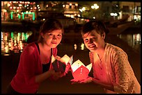 Two women lighted by candle box at night. Hoi An, Vietnam (color)
