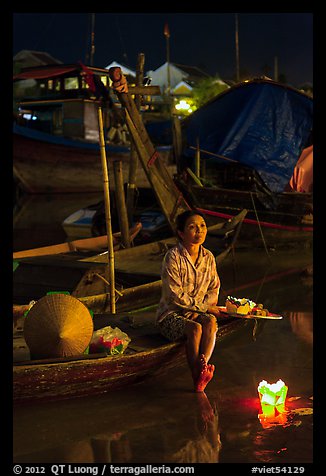 Woman sitting in boat with floating candles by night. Hoi An, Vietnam