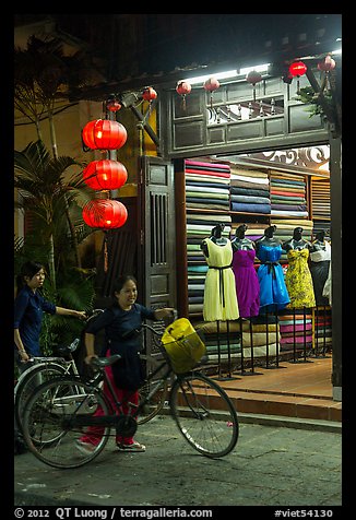 Women with bicycles in front of taylor shop. Hoi An, Vietnam (color)