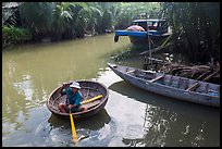 Man rows coracle boat in river channel. Hoi An, Vietnam (color)