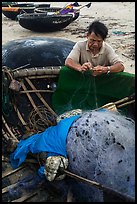 Fisherman repairing net on beach. Da Nang, Vietnam (color)
