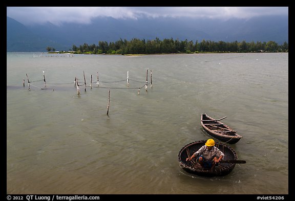 Man rowing coracle boat in lagoon. Vietnam (color)