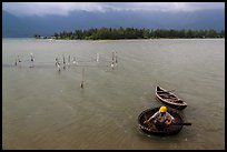 Man rowing coracle boat in lagoon. Vietnam (color)