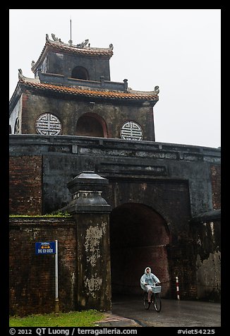 Biking through citadel gated entrance in the rain. Hue, Vietnam