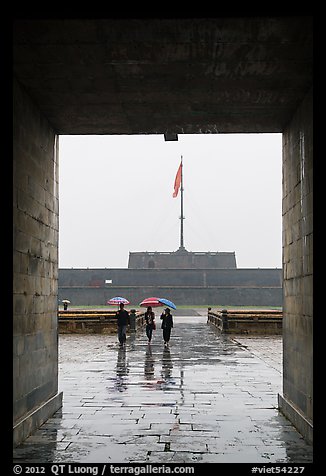 Tourists with unbrellas and flag monument, citadel. Hue, Vietnam (color)