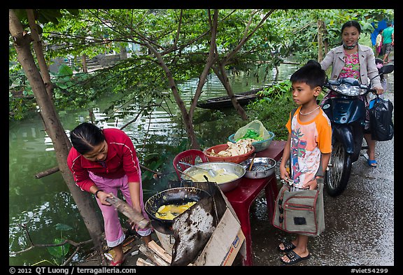 Boy waiting for donut coooked near canal, Thanh Toan. Hue, Vietnam (color)